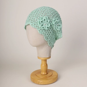 Detail of hand-crocheted light green beanie featuring 3D floral accents and pearls