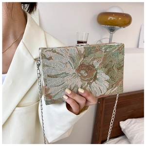 Close-up of vintage floral pattern and silver chain on elegant rectangular crossbody bag