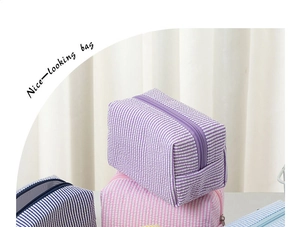 Macro shot of seersucker makeup bags showing striped fabric texture and zipper detail