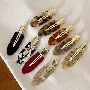 9-piece set of acetate hair clips in tortoiseshell and marble patterns on white silk