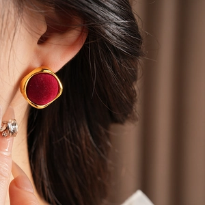 Gros plan d'une boucle d'oreille carrée dorée avec velours rouge sur un mannequin