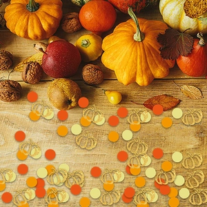 Autumn harvest party confetti with gold and orange pumpkin shapes on a wooden table