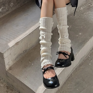 Détail de jambières blanches avec nœuds portées avec des chaussures Mary Jane noires