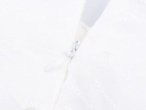 Détail de la fermeture éclair invisible et broderie sur une robe d'été blanche