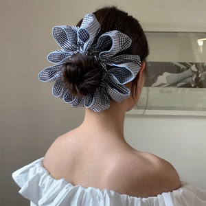 Detail of a large Gingham checkered scrunchie styled on a low hair bun for women