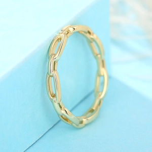 Gros plan d'une bague chaîne dorée ajourée sur un présentoir géométrique bleu clair