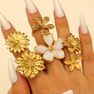 Detail shot of a six-piece gold flower ring set with white enamel and sunflower designs
