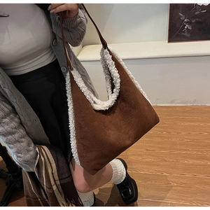 Brown tote bag with white plush trim shown held by a model in a minimalist indoor setting