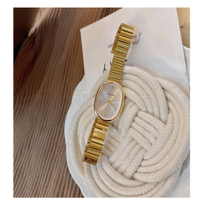 Detail view of oval gold watch dial with silver sunray pattern and metal link strap