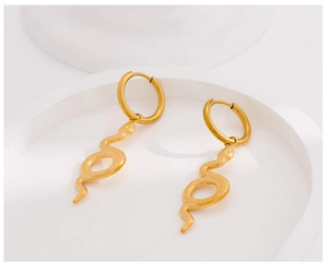 Close-up of gold snake earrings with hoop closures on a minimalist white display