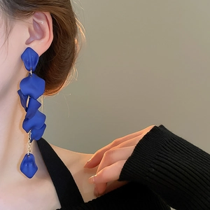 Detailed view of long navy blue petal tassel earrings with gold chain on model neck line