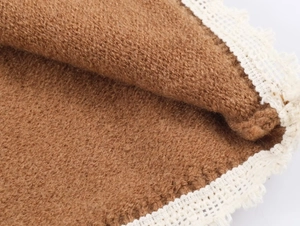 Détail du tissu en velours marron avec bordure en dentelle blanche sur le textile