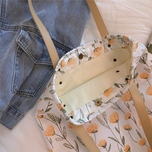 Détail d'un cabas en toile fleurie avec anses en cuir et fermeture à boucle magnétique