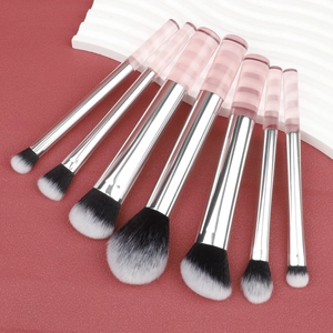 Dettaglio di 7 pennelli da trucco con manici a righe rosa e setole bicolore morbide
