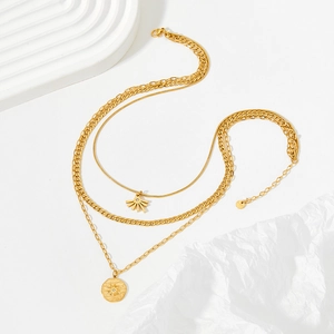 Detailed close-up of triple-layered golden necklace with sunburst coin pendant and charms