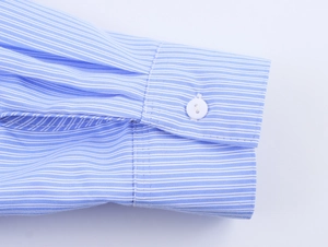 Dettaglio macro del polsino della camicia a righe con un classico bottone bianco