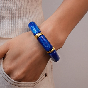 Detailed view of wide dark blue marble acrylic bangle with gold accents on wrist