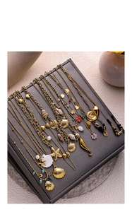Détail de colliers en laiton doré avec pendentifs coquillage, étoile de mer et perle
