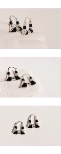 Detailed views of black enamel trapezoid earrings with textured gold relief accents