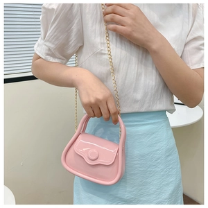 Detailed view of pink macaron jelly bag with golden chain and glossy finish on model