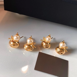 Détail de boucles d'oreilles gourde dorées avec zircons et perles blanches élégantes