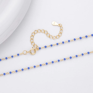 Detailed close-up of S925 sterling silver stamp on a gold chain with blue beads