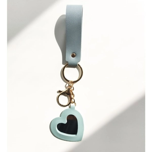 Detail view of light blue leather keychain with heart-shaped mirror and gold metal ring