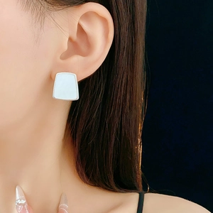 Gros plan d'une boucle d'oreille géométrique en résine argentée de forme trapèze sur mannequin