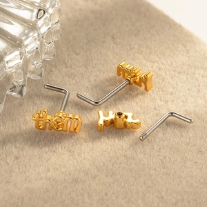 Golden L-shaped nose studs featuring letter pendants 'them', 'they', and 'her' on felt