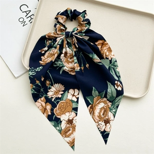 Floral print hair scrunchie with long ribbons on a minimalist display tray