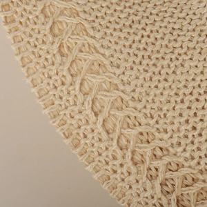 Close-up of beige knitted wide brim sun hat showing textured cable knit stitch pattern