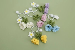 Detail of five colorful crochet lily of the valley keychains with bells on green background