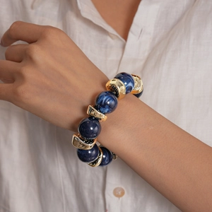 Dettaglio del bracciale con perle marmorizzate blu e inserti metallici dorati su modella