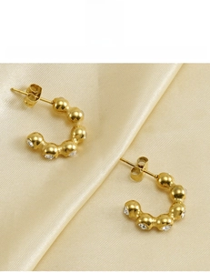 Macro detail of 18K gold-plated U-shaped earrings with zircon stones on silk fabric