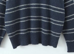 Detailed macro view of navy striped knit sweater with ribbed hem and wool texture fabric