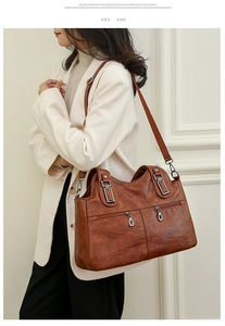 Detail of dark brown leather handbag featuring dual vertical zippers and pebbled texture