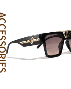 Detail of square black sunglasses featuring gold heart accents and dark gradient lenses