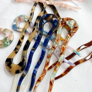 Minimalist U-shaped acetate hairpins with tortoise and marble patterns on white fabric