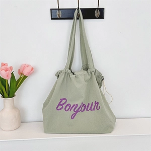 Detail of green waffle fabric tote bag featuring purple Bonjour lettering and drawstring