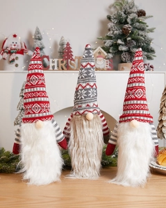 Detailed view of three Christmas gnomes with knitted hats and white beards on a wooden table