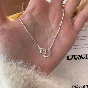 Detailed shot of silver double ring necklace featuring smooth and twisted geometric links