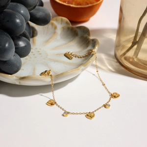 Detail of 18K gold-plated stainless steel bracelet with heart charms and clear zircons