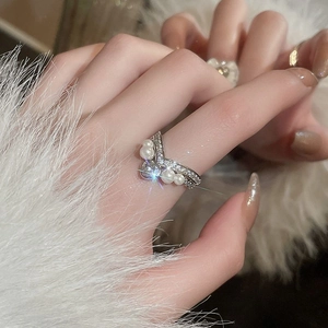Close-up of V-shaped silver ring with white pearls and heart-shaped sparkling gemstone