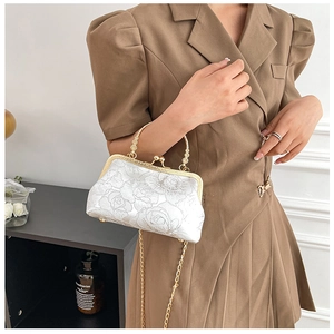 Detail of white floral cheongsam clutch with pearl handle and golden chain strap