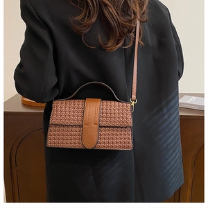 Close-up of brown woven leather texture on crossbody bag worn over a black blazer