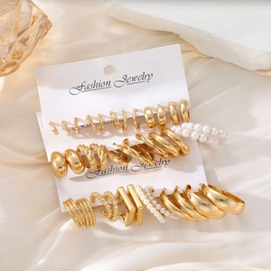 Detailed view of an 8-piece golden geometric metal and pearl earring set on a white card