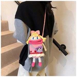 Detail of pink knitted crossbody bag with a cartoon doll design and purple bear accent
