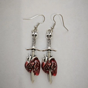 Gothic dagger earrings with skull and red anatomical heart detail on white background