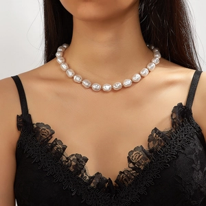 Detail view of large irregular baroque pearl necklace worn on model neck