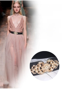 Detail of black elastic corset belt with golden floral buckle and white pearls